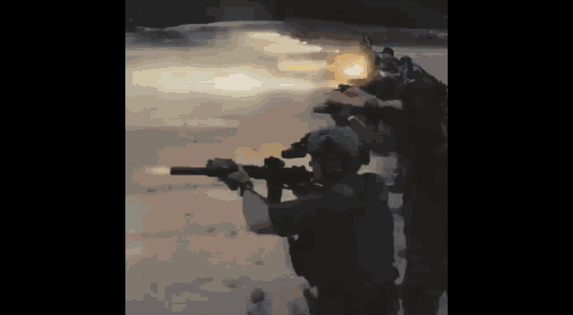 a group of soldiers are standing in a line holding guns in their hands .