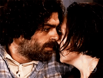 a man with a beard and a woman with short hair are kissing