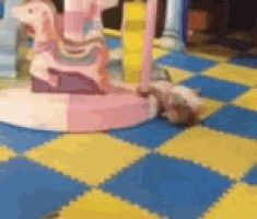 a child is laying on the floor in front of a pink carousel horse .