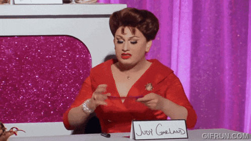 a woman in a red dress is sitting at a table with a sign that says judy greland on it