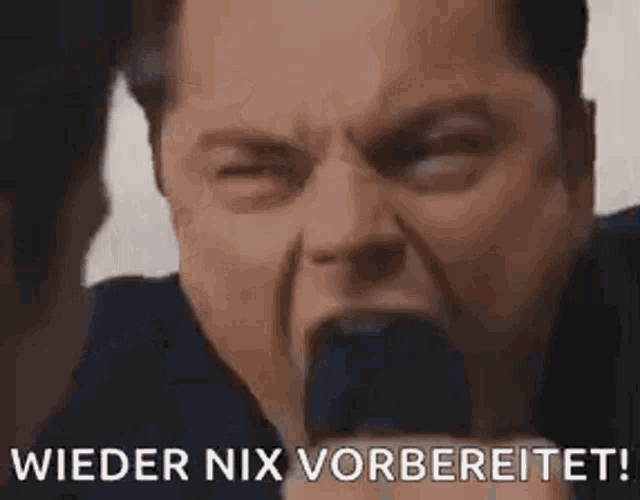 a man is holding a microphone in his mouth and saying `` wieder nix vorbereitet '' .