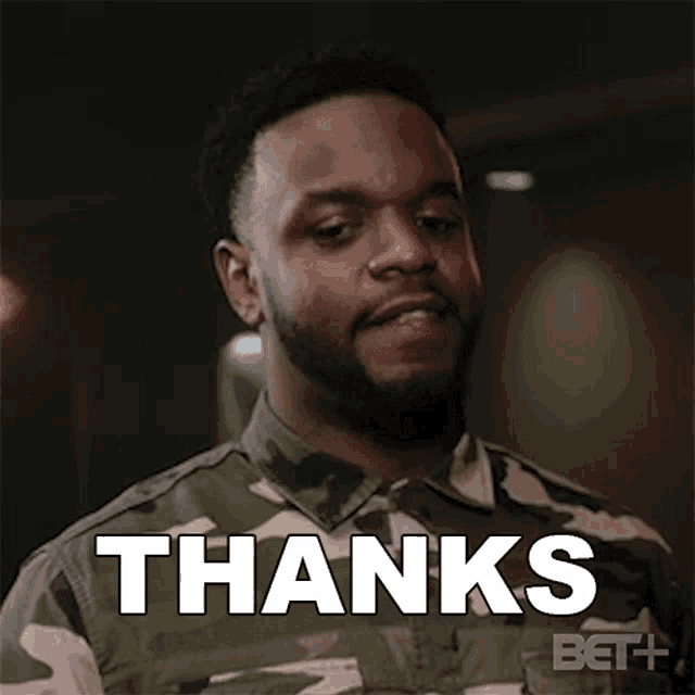 a man with a beard is wearing a camouflage shirt and saying thanks .