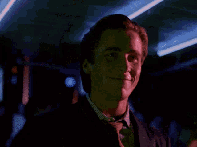 a man in a suit and tie is smiling with a red light behind him