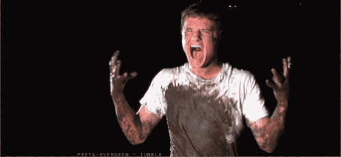 a man in a white shirt is covered in mud and has his mouth open