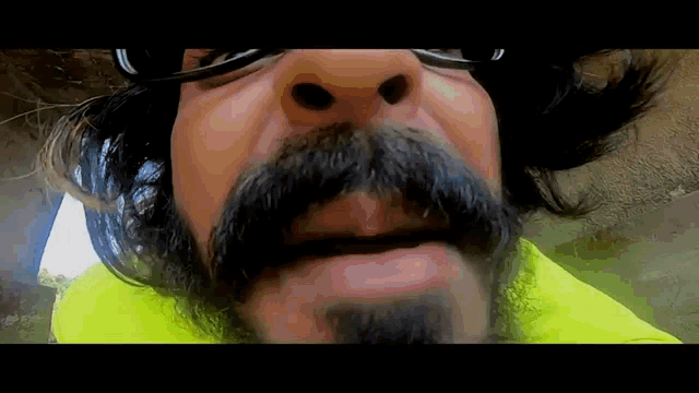 a close up of a man 's face with glasses and a mustache