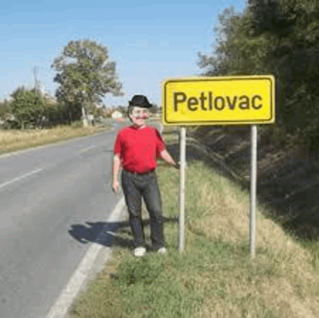 a man in a red shirt is standing in front of a yellow sign that says petlovac