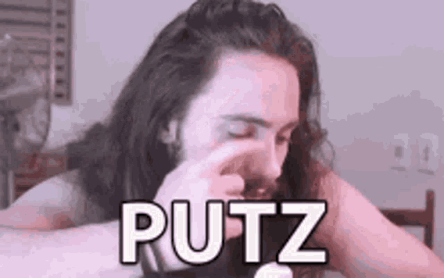 a man with long hair and a beard is covering his nose with his hand and says putz .
