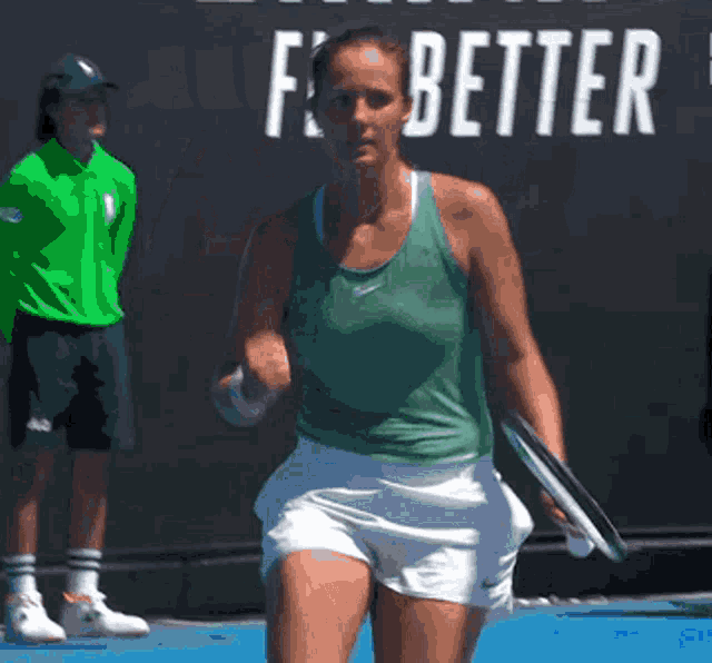 a woman in a green nike tank top is holding a tennis racquet