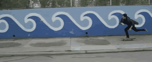 a man is riding a skateboard in front of a blue wall with white waves