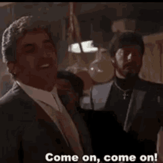 a man in a suit and tie is standing in front of a yellow balloon and says come on come on .