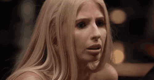 a close up of a woman 's face with long blonde hair making a funny face .