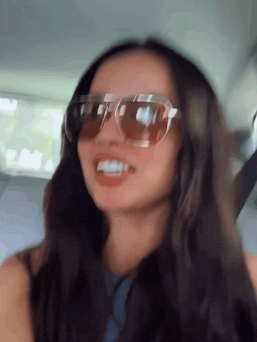 a blurry picture of a woman wearing sunglasses and smiling