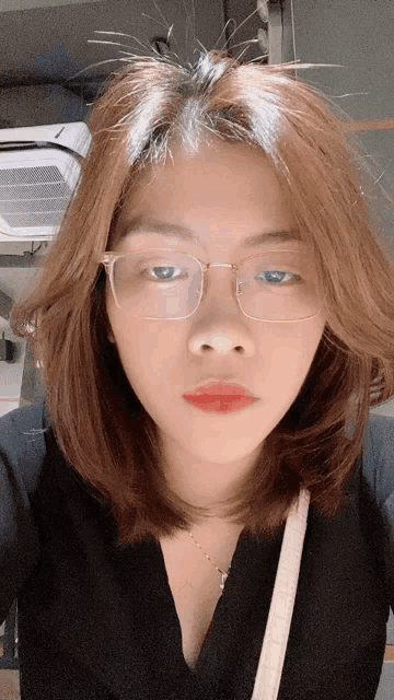 a young woman wearing glasses and red lipstick looks at the camera