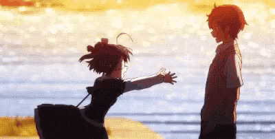 a boy and a girl are standing next to each other in front of the water .
