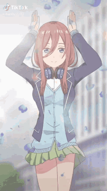 a girl with headphones on her head is standing in front of a wall .