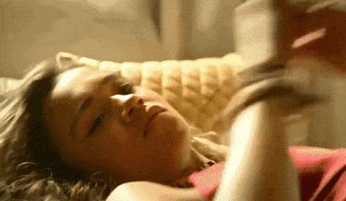 a woman is laying down on a couch with her eyes closed .