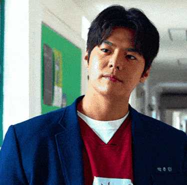 a man wearing a blue jacket and a red sweater has a name tag that says ' 박우민 '