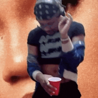 a man in a crop top is holding a red cup .