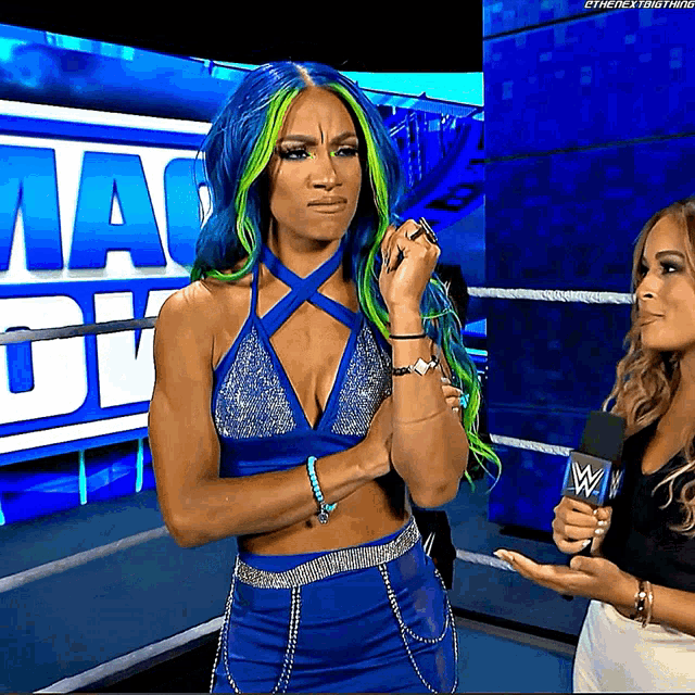 a woman with blue and green hair is standing in front of a sign that says ' mackdown '
