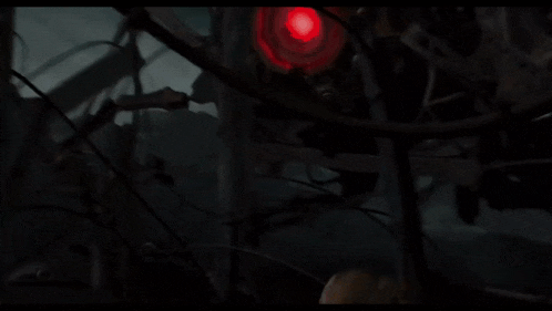 a spider with a red light on its head is surrounded by barbed wire in the dark