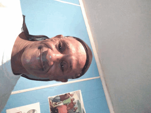 a man is smiling in front of a blue wall with a picture of a group of people on it