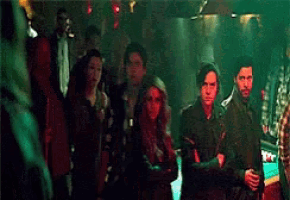 a group of people are standing in a dark room in a bar .