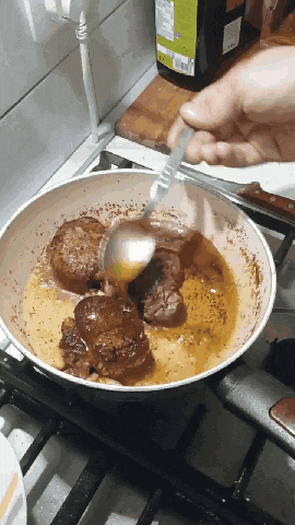 a person is stirring a pan of food with a spoon