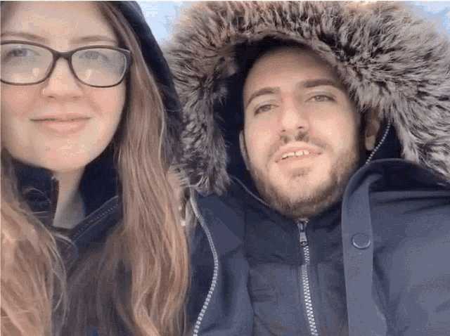 a man and a woman are posing for a picture and the man has a fur hood
