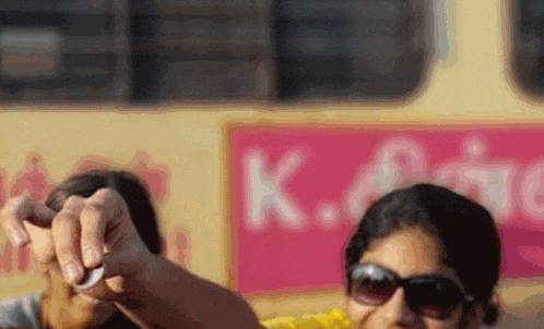 a woman wearing sunglasses is pointing at something in front of a sign that says k