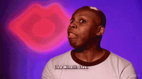 a man in a white shirt is making a funny face in front of a pink heart shaped object .