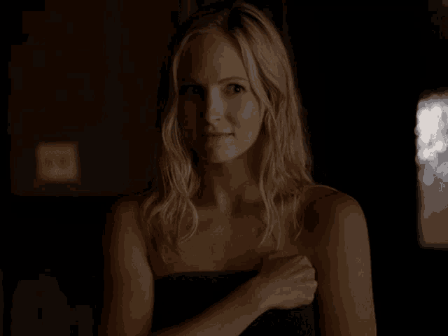 a naked woman wrapped in a towel is standing in the dark .
