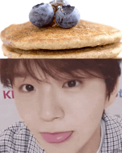 a close up of a person 's face next to a stack of pancakes and blueberries