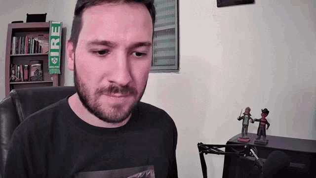 a man with a beard wearing a black shirt that says ire