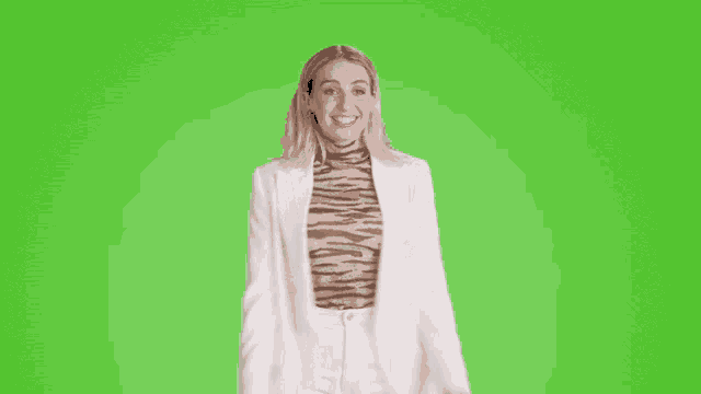 a woman wearing a zebra print top and a white jacket is smiling