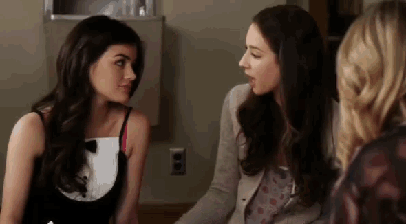 two women are sitting next to each other and talking to each other in a room .