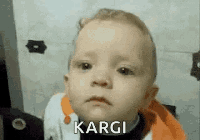 a baby is making a funny face and the word kargi is on his face .