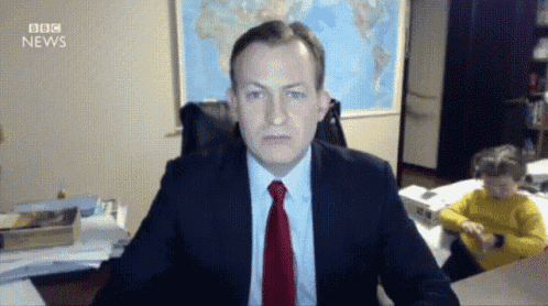 a man in a suit and tie sits at a desk with bbc news written above him