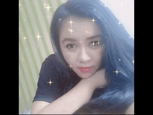 a woman with long blue hair is taking a selfie with her hand on her chin