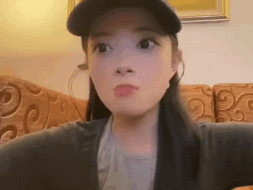 a woman wearing a hat is sitting on a couch .