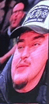 a man wearing a hat is sitting in a stadium with a red background .