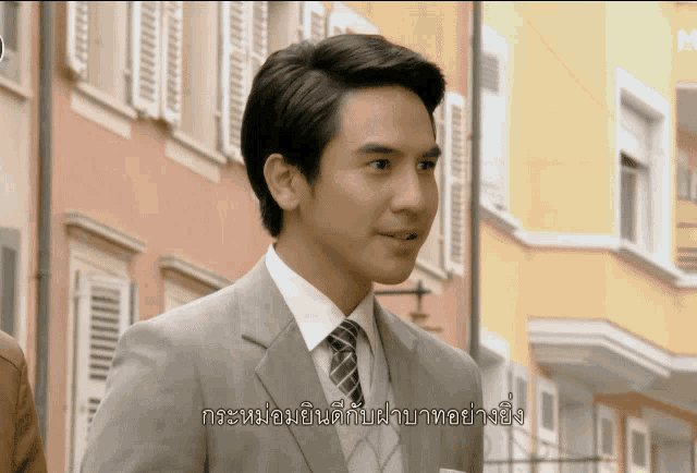 a man in a suit and tie is standing in front of a building with a foreign language written on it
