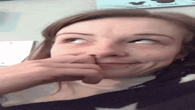 a woman is making a funny face while holding her finger to her nose