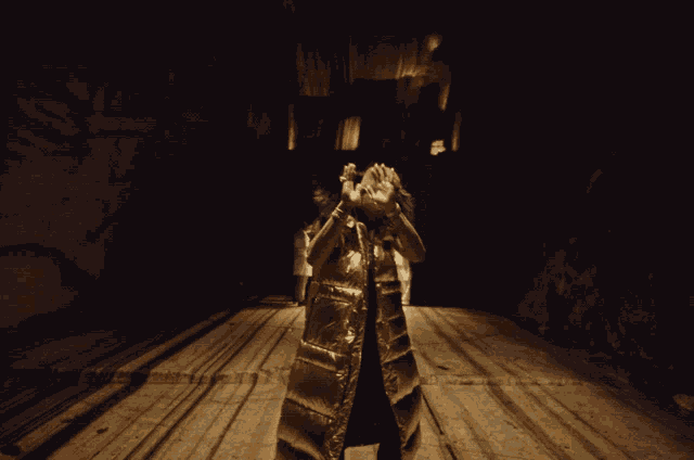a man in a gold costume stands in a dark room