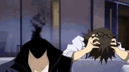 a man with glasses is laying on a bed holding his head .