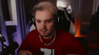 a man wearing headphones and a necklace is sitting in front of a microphone in a room .