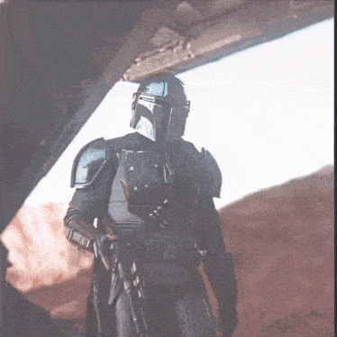 a man in armor is holding a gun in the desert ..