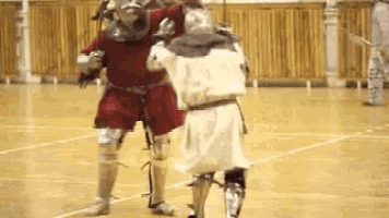 a man in armor is fighting another man on a basketball court .