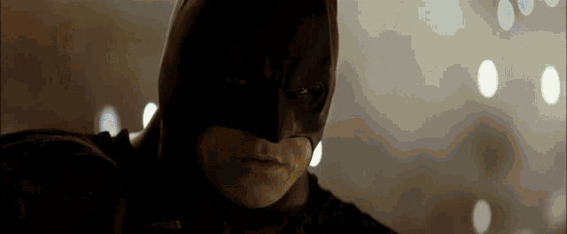 a man in a batman mask looks at the camera