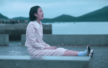 a woman in a pink dress is sitting on the ground with her legs crossed