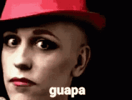 a bald woman wearing a red hat with the word guapa written on it